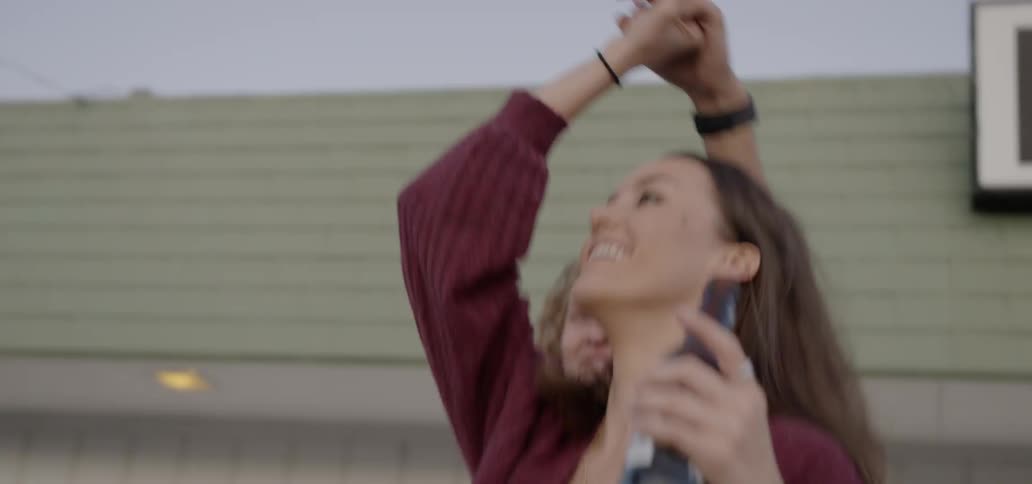 A woman holds a beer and dances with a man