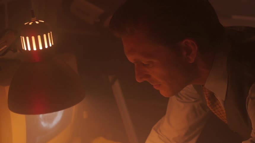 A man leaning over to type on a computer