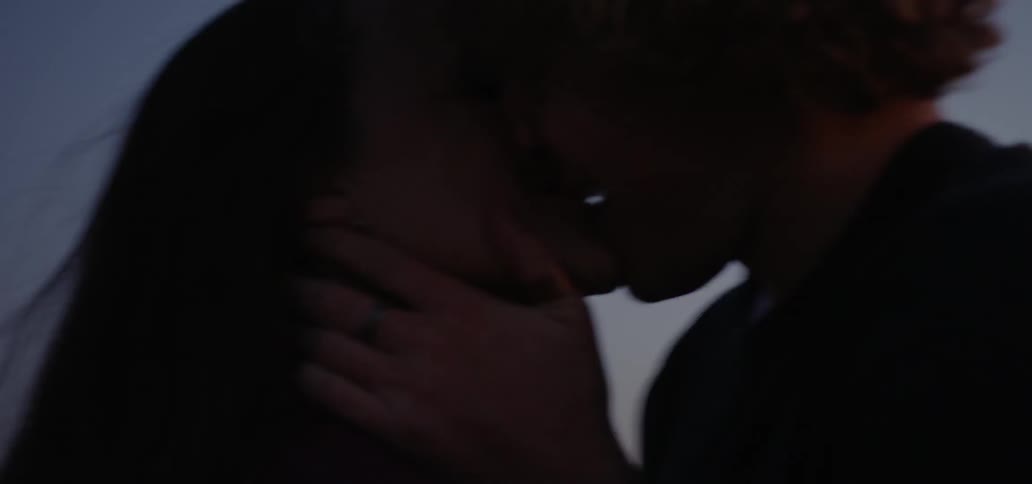 A young couple kissing energetically in the evening