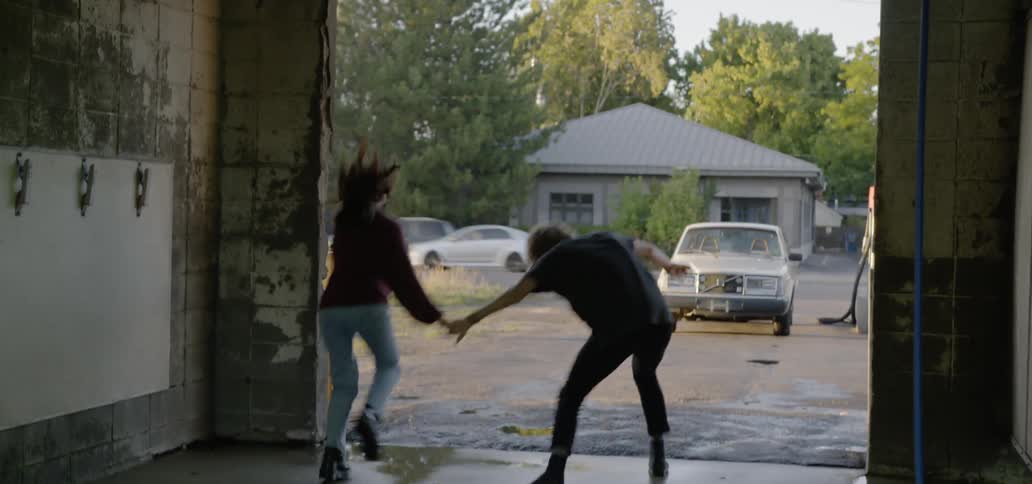 A man and woman running out of a garage to a car