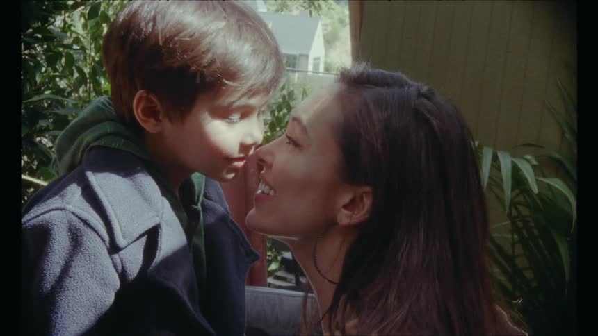 Mother and son rub noses against each other and smile