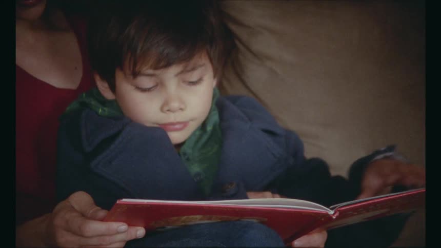 Mother and son sitting on a couch reading a book