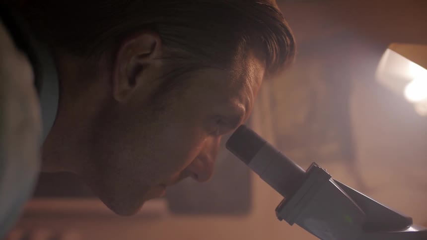 A man looks into a microscope eyepiece
