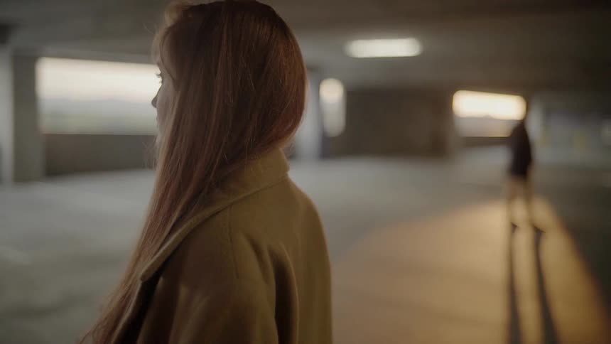 A red haired female in a parking building with a male nearby
