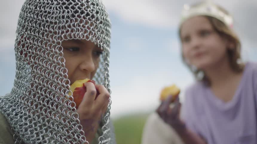 Two children playing dress up and eating apples