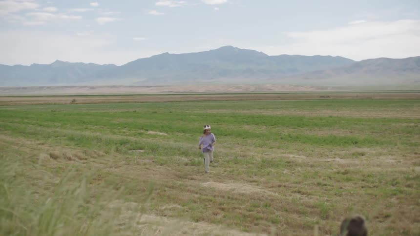 A child runs through a field toward other children