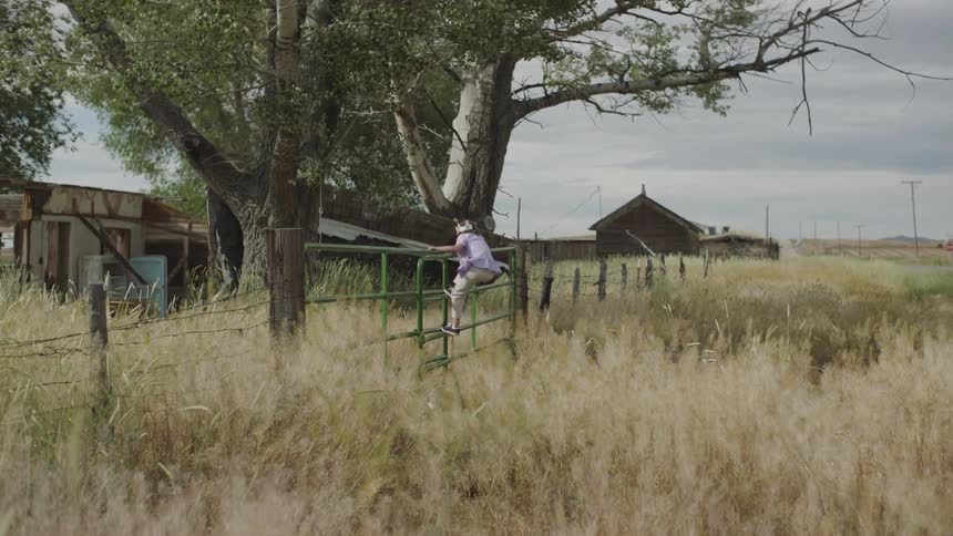 A young girl climbs over the green fence to the field