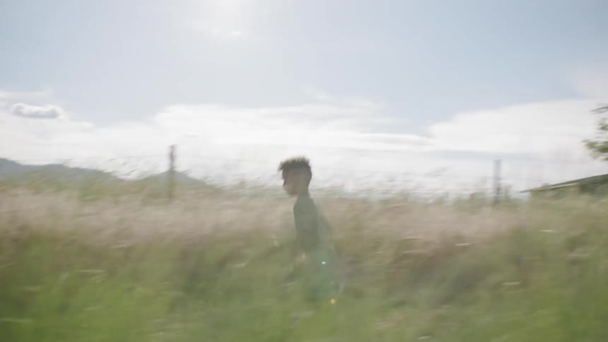 A boy runs through a field of tall grass