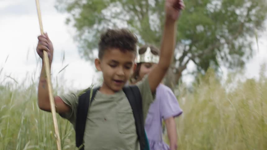 Boys and girls walk through field of tall grass