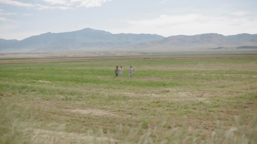 Three kids running and playing on an empty field
