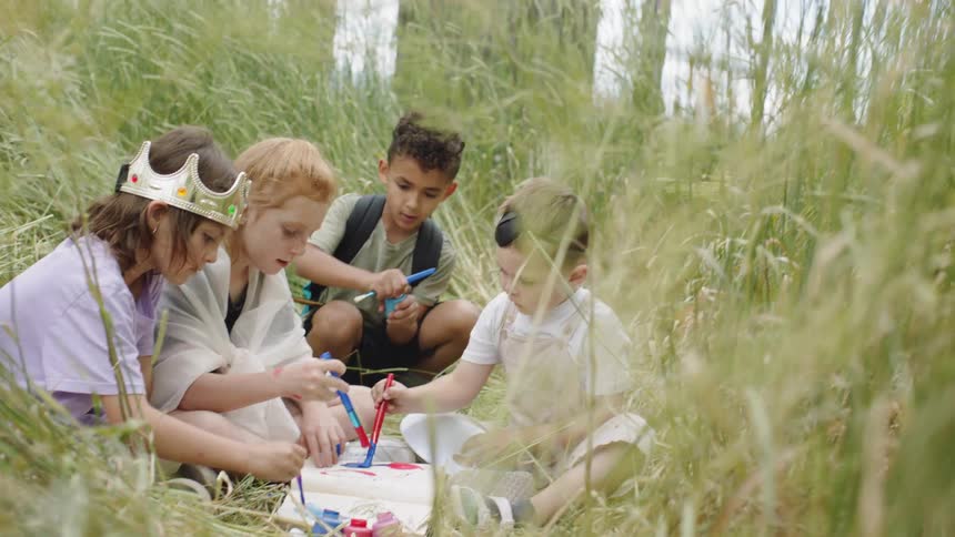 Kids sitting in grass painting