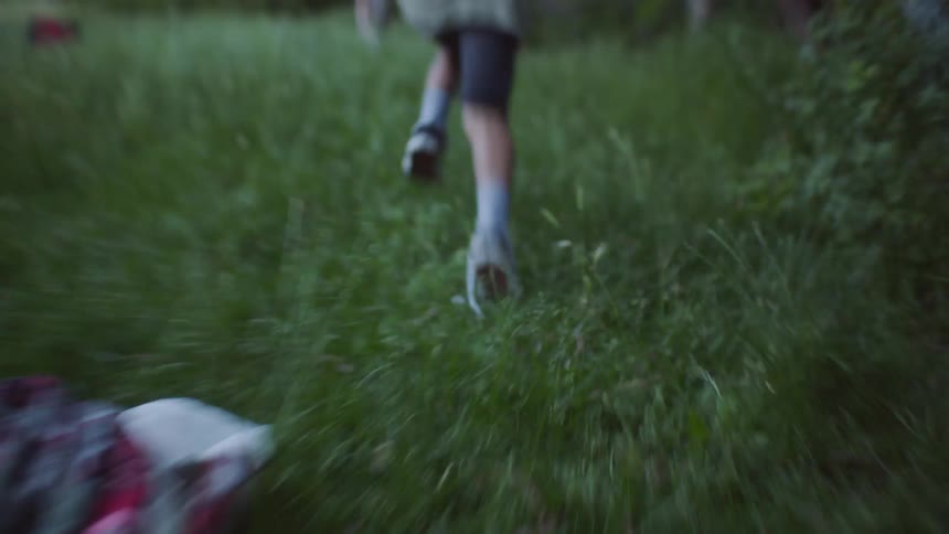 Young kids run across a grassy field