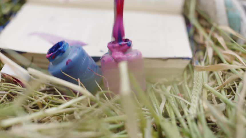 A child spreads blue and pink paint all over an open book