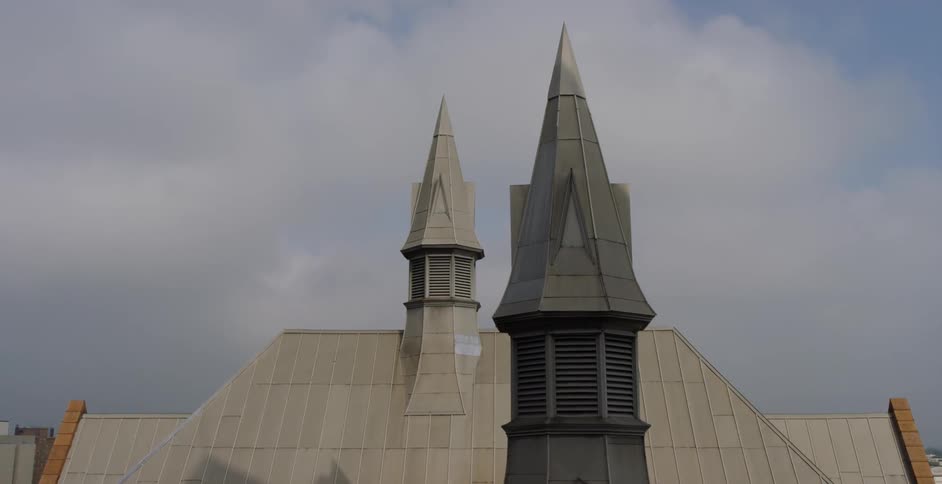 Two spires tower over the roof of a building