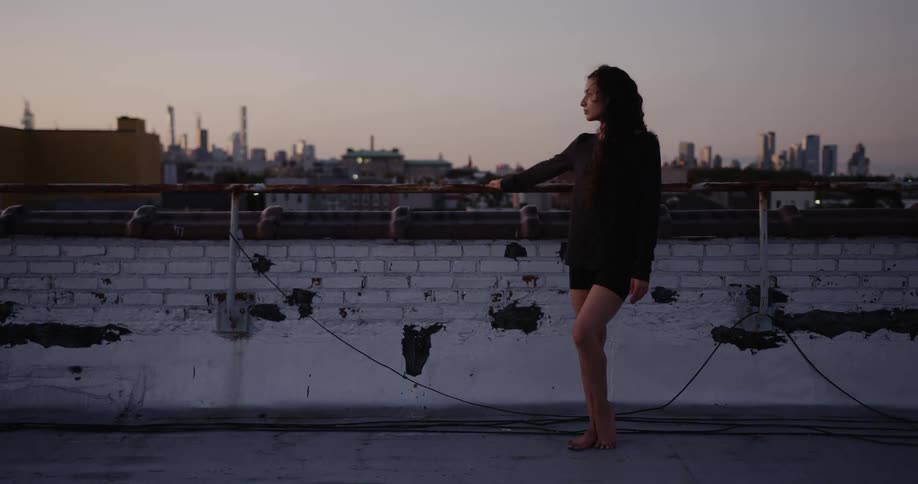 A woman stands next to the edge of a roof
