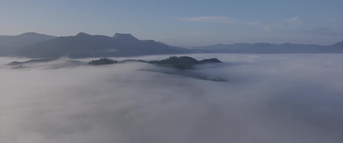 The camera flies over cloudy mountains