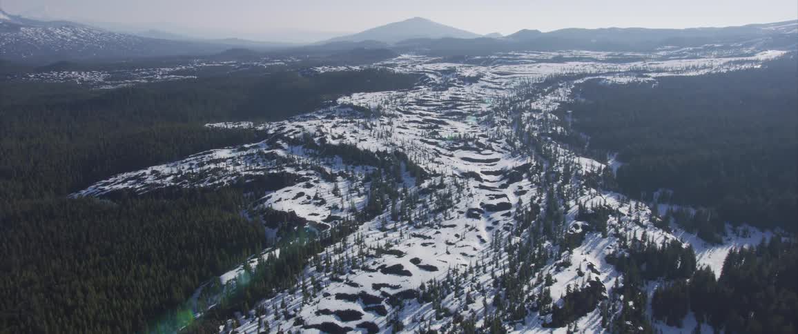 Snow covers a rocky expanse that runs through a forest