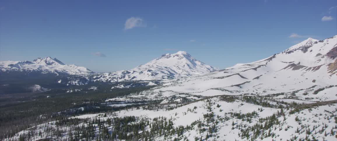Snow and pine trees cover a mountain landscape