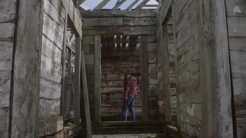 A man walking into an old dilapidated house