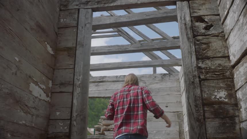 A man walks through a worn shack