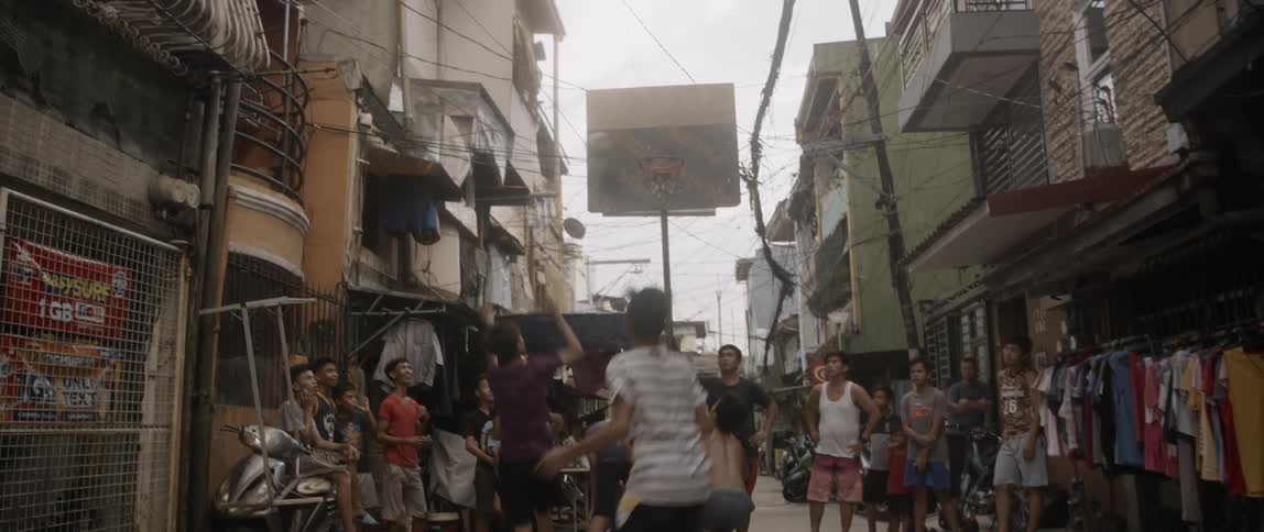 A large group of kids playing basketball on a urban street