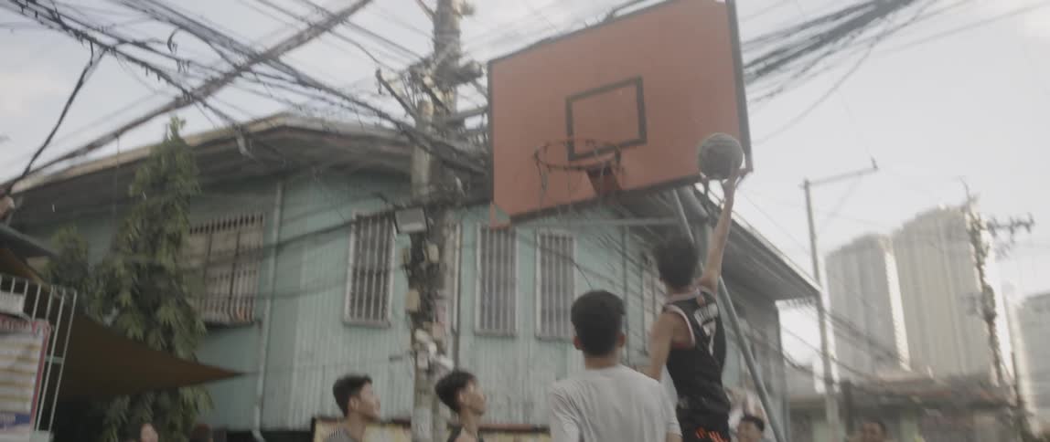Teenagers play street ball against each other in the shanty town during the daytime