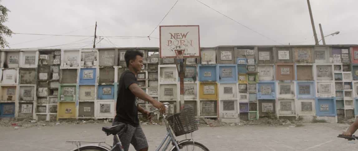 A man walks past a basketball hoop in the cemetery