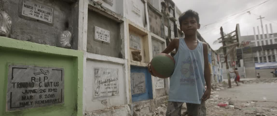 A boy holding a ball before a memorial wall