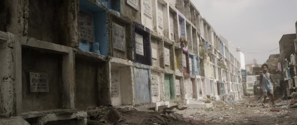 A child wanders down a street in a slum