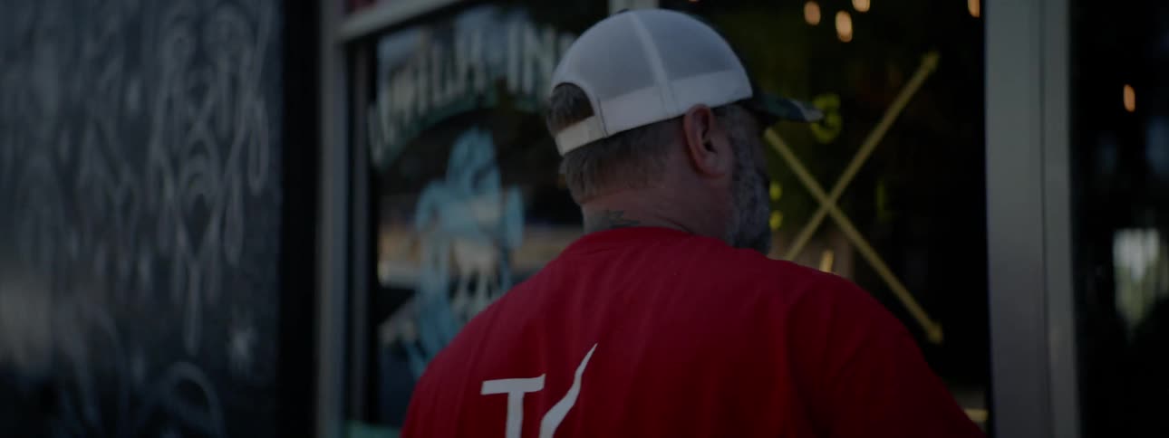 Man wearing cap and red shirt enters bar on a sunny day
