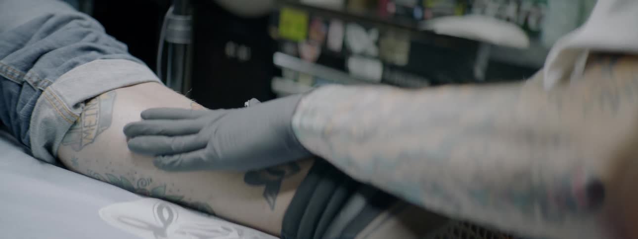A person working on another person's tattoo