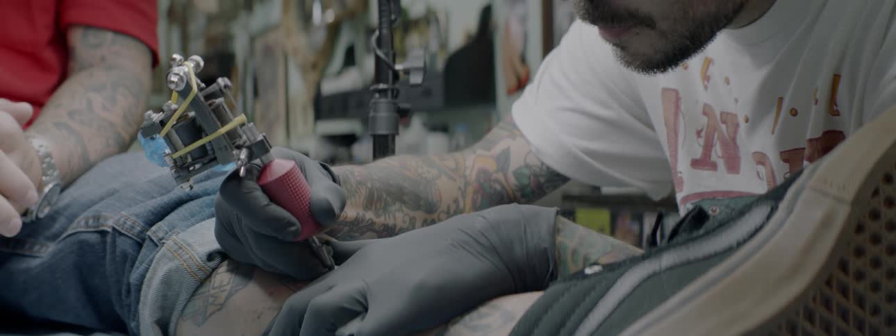 Tattoo artist working on a mans leg