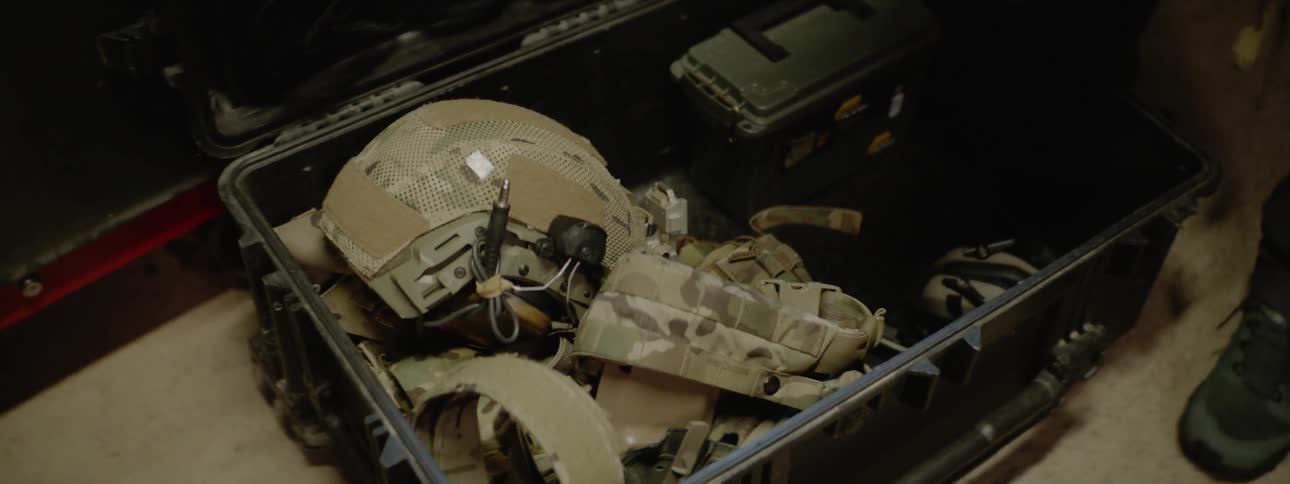A man places his helmet and combat gear in a foot locker