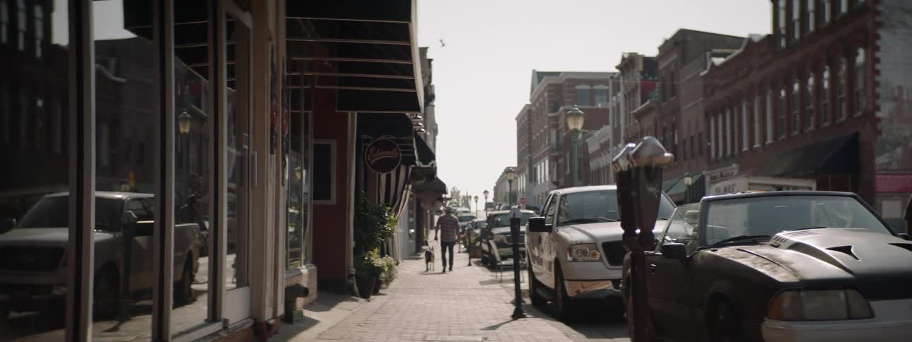 Man walks dog on downtown sidewalk in small town