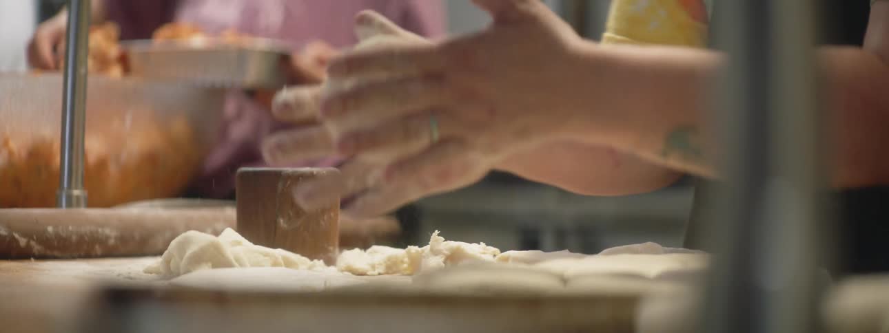 People work in a kitchen preparing biscuits