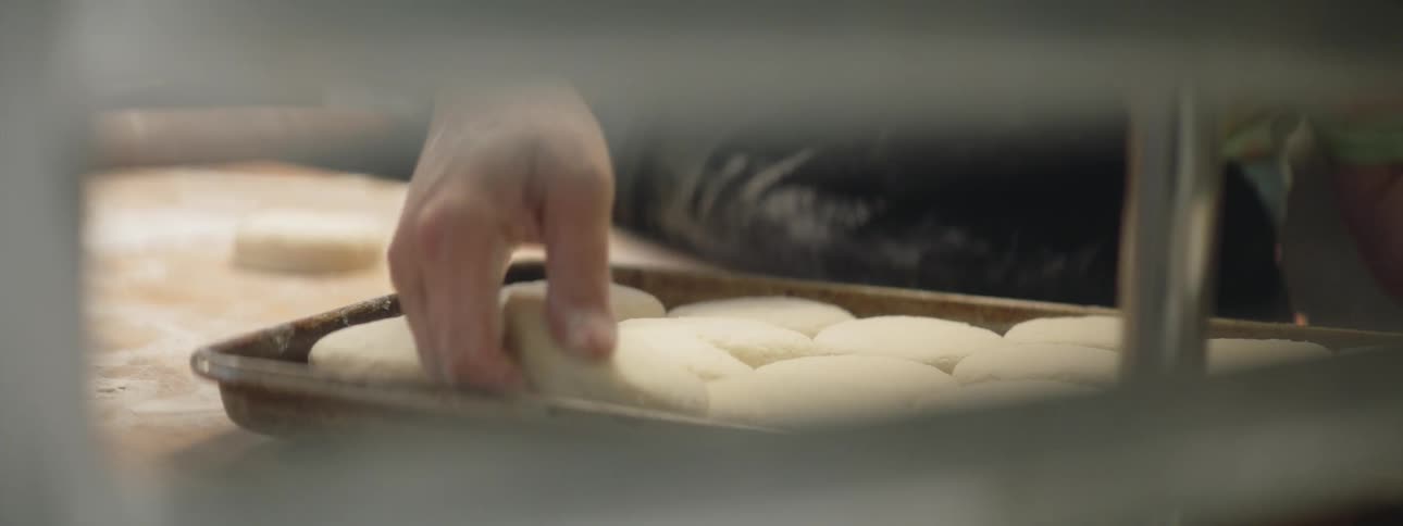 A person placing dough into a pan in a kitchen