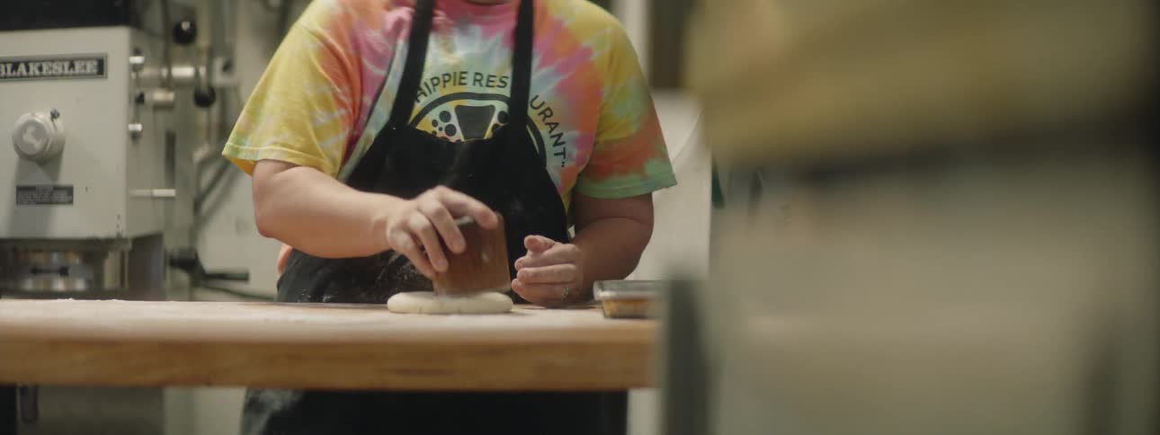 A man is flattening dough in a restaurant