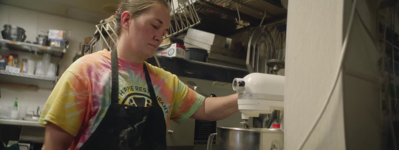A baker using a kitchenaid mixer in a professional kitchen