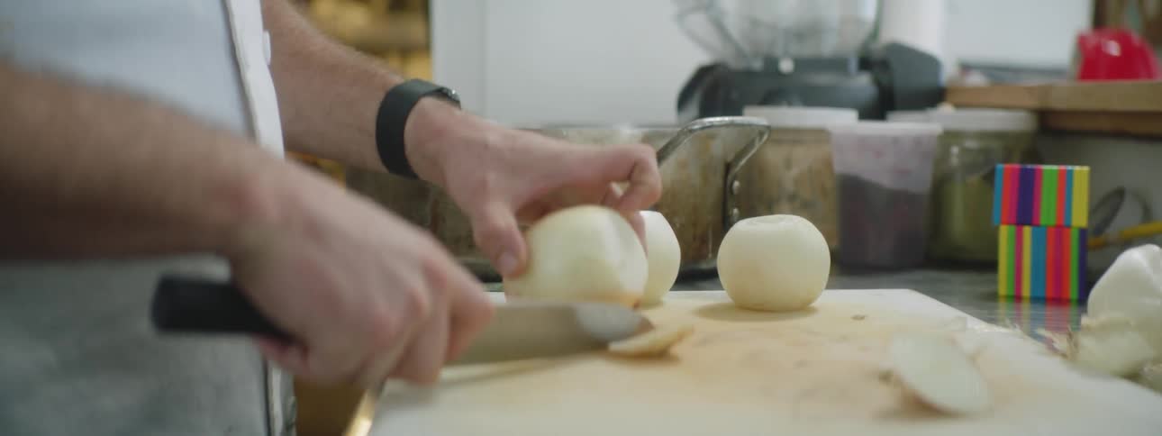 A man is cutting onions in the kitchen