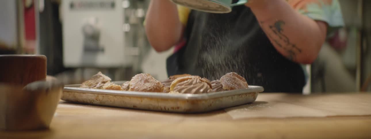 A woman puts sugar on her baking