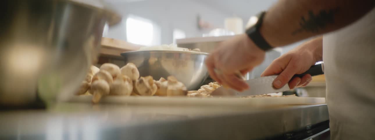 A man slicing mushrooms in a kitchen