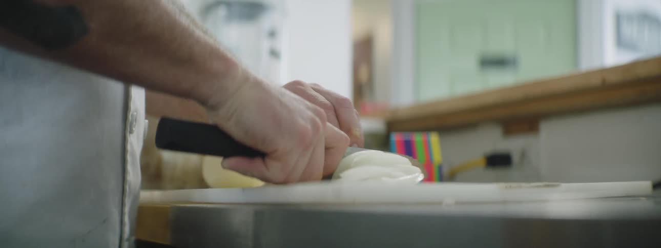 A man slicing onions in a kitchen