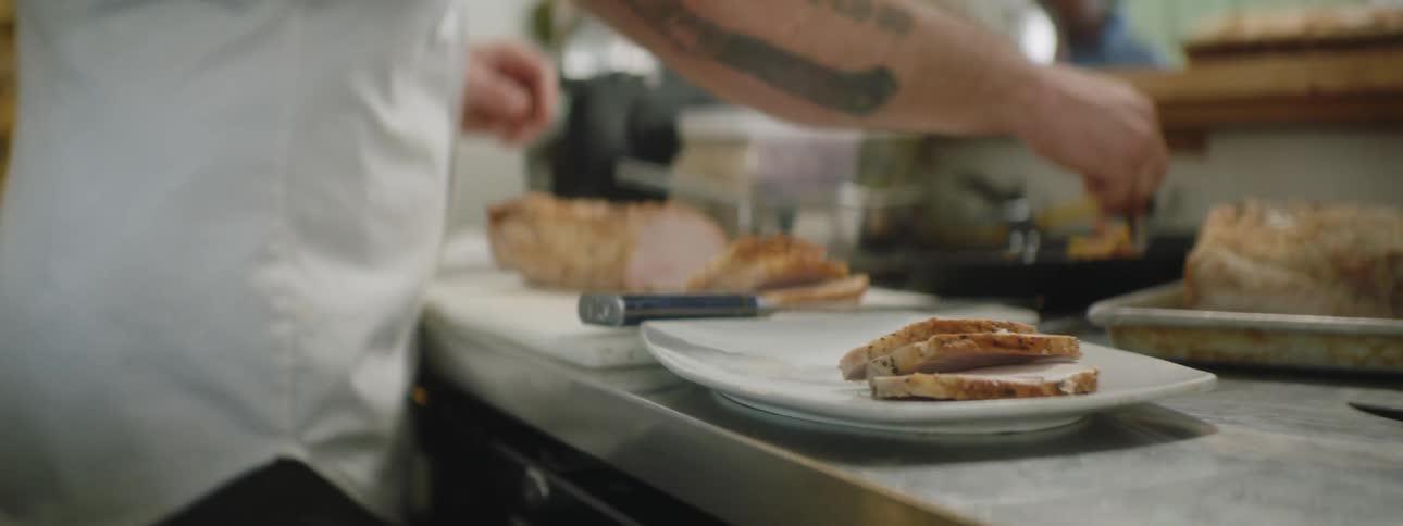 A tattooed chef plating food