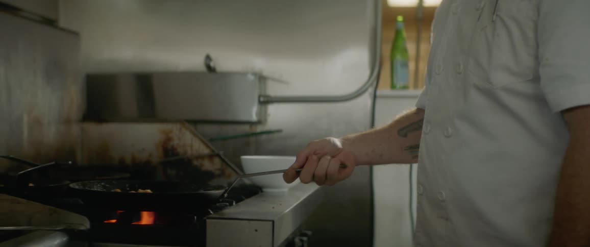A chef cooking something in a pan in a kitchen