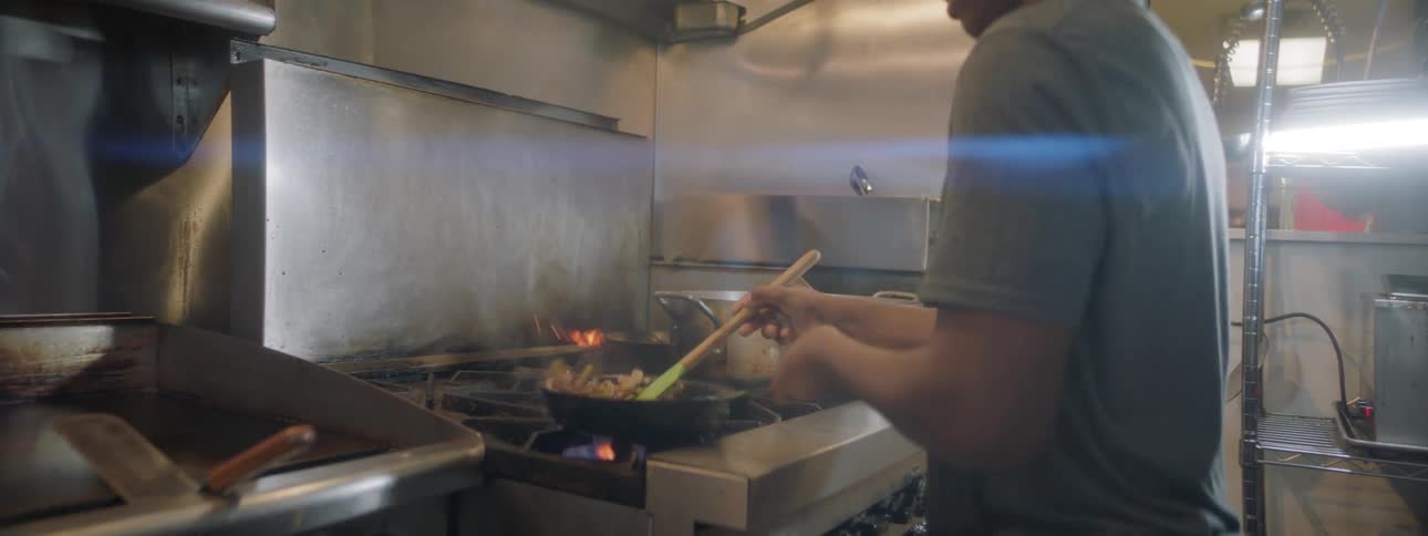 Chef stirs pan on stove