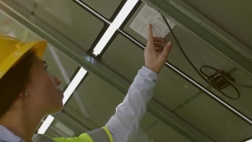 A young woman in a hard hat reads some text