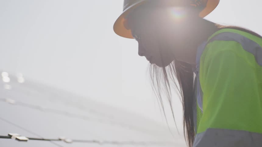 Woman in a hard hat examining plans resting on a solar panel