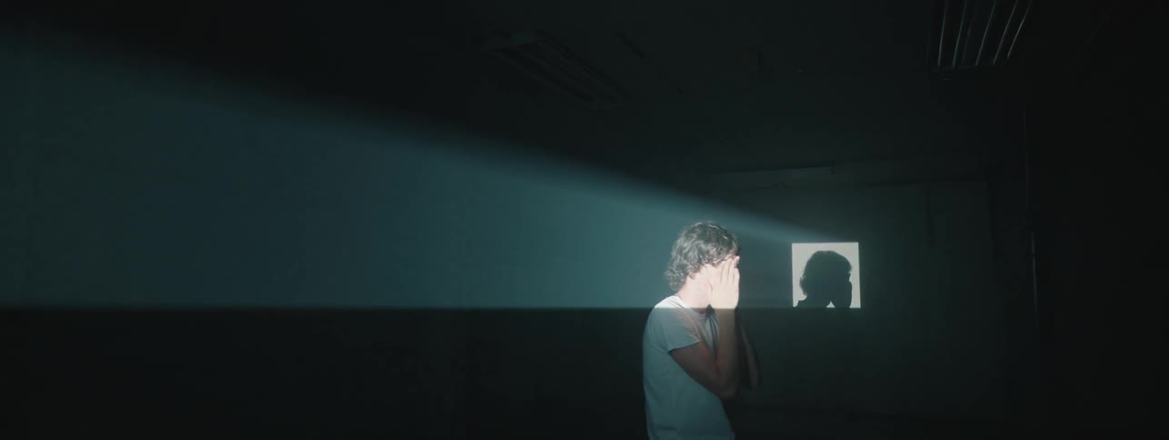 Man sits in dark room highlighted by light from window