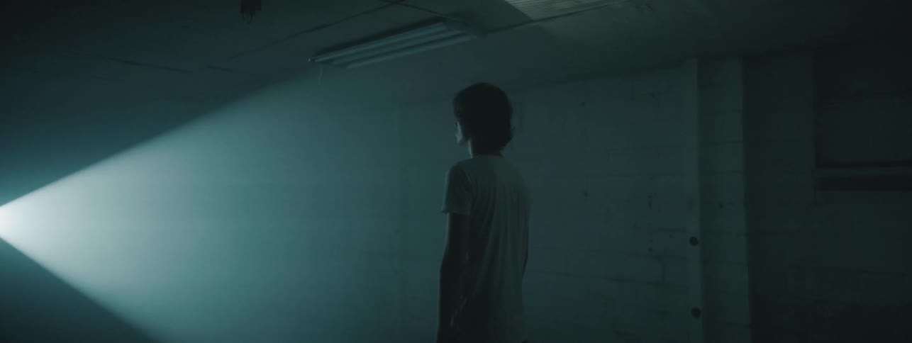 A man stands in a dark room with lights flashing on him