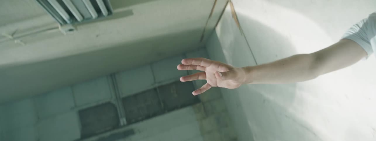 A boy lies on a floor with his hand in the air while a strobe light flashes